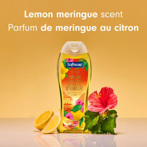 A bottle of Softsoap Amalfi Orchards body wash, centered between lemon slices and a bright pink hibiscus flower. The text above reads "Lemon meringue scent" and "Parfum de meringue au citron."