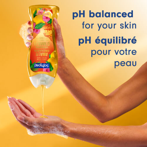 Against a warm yellow background, a person pours golden-yellow shower gel from a bottle into their hand. The text reads: "pH-balanced for your skin."