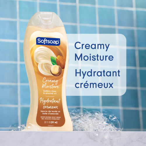 A bottle of Softsoap with creamy shea and almond oil, set in a blue-tiled shower and surrounded by bubbles. The text, in English and French, reads: Creamy Moisture.
