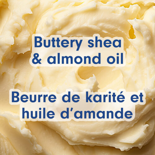 Close-up on the thick, whipped texture of ivory-colored shea butter. Text in English and French: Buttery shea & almond oil.