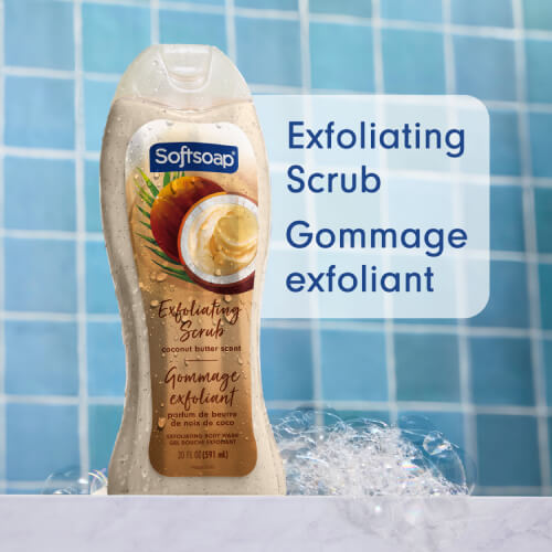 A bottle of Softsoap Coconut Butter Exfoliating Scrub in a blue-tiled shower, surrounded by bubbles. The text, in English and French, reads: Exfoliating scrub, Gommage exfoliant.