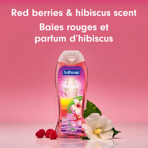 The Fiji Nights body wash bottle sits on a pink surface next to fresh red raspberries and a white hibiscus flower. Large text above reads "Red berries & hibiscus scent" and "Baies rouges et parfum d’hibiscus."