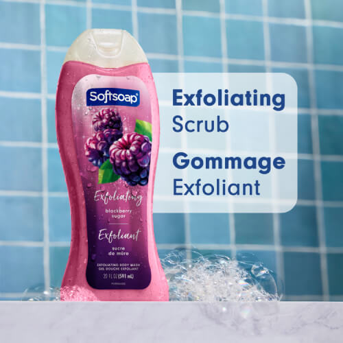 A bottle of Softsoap Blackberry Sugar body wash resting on a marble surface with soap bubbles. Background features blue bathroom tiles. Text overlay reads "Exfoliating Scrub" and "Gommage Exfoliant."