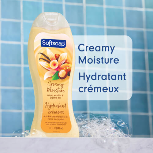 A 20-ounce bottle of Softsoap Warm Vanilla and Jojoba Oil Moisturizing Body Wash against a blue tiled background with bubbles. Large text to the right reads "Creamy Moisture" and the French translation "Hydratant crémeux."